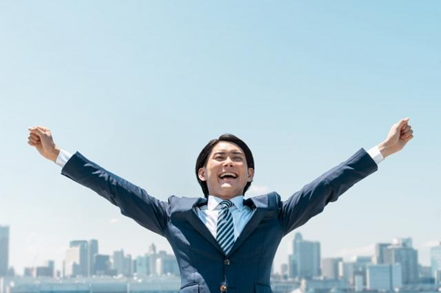 青空で両手を上げる男性