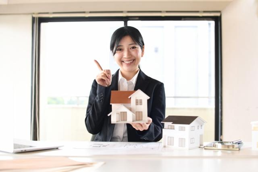 家の模型を持つ笑顔の女性