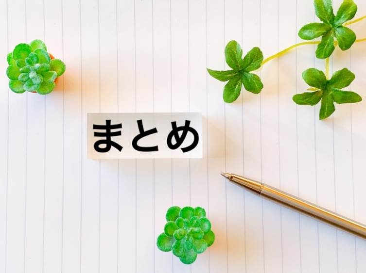 クローバーと「まとめ」の文字が置かれたノートとペン