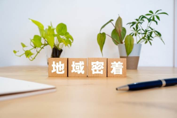 「地域密着」の文字ブロックと観葉植物
