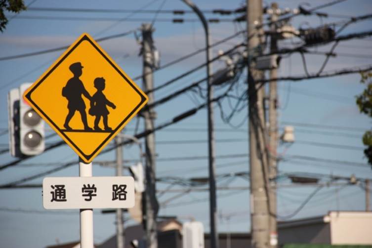 通学路を示す標識と電柱が立ち並ぶ街並み
