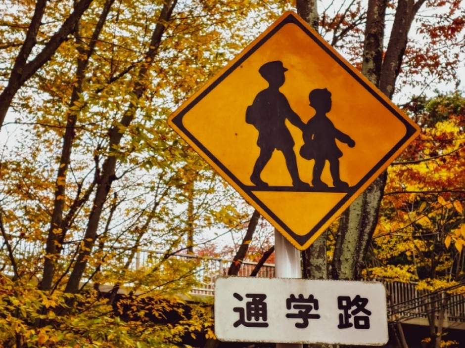 紅葉の木々の中に設置された通学路の標識