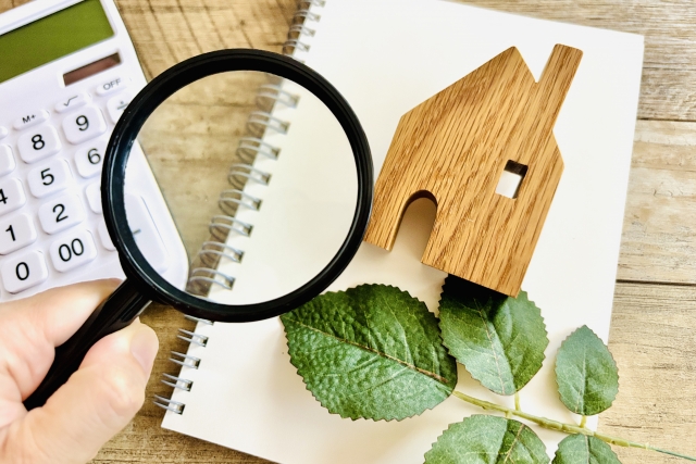 家の模型と虫眼鏡とノート、電卓